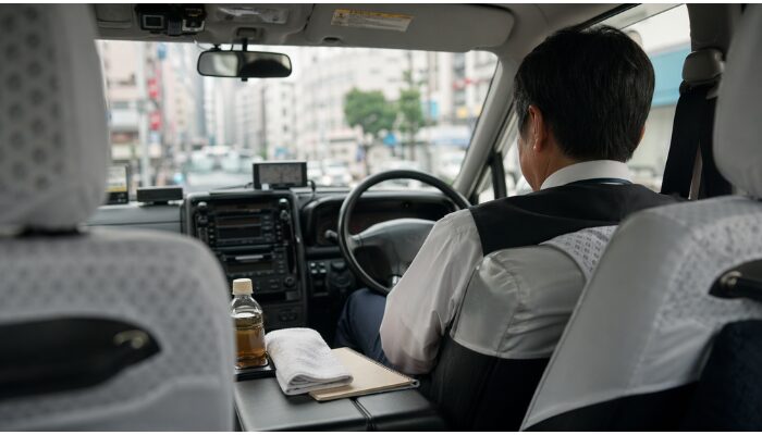 タクシー車内で飲み物やタオルを置きながら短い休憩を取る運転手の様子